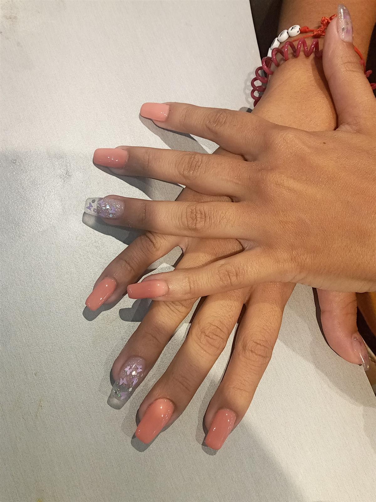 Manos con uñas nude y detalle brillante